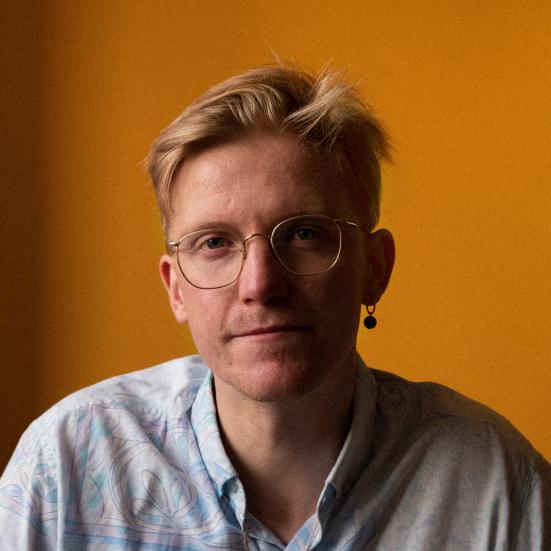 Mand i skjorte og med briller kigger på kameraet