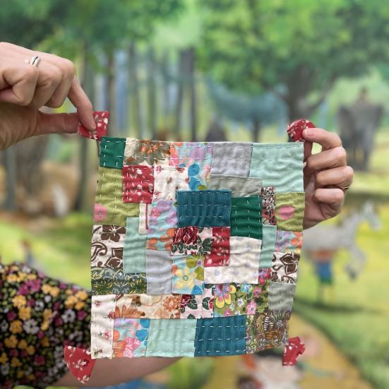 Hænder der holder et patchwork af stof lapper op