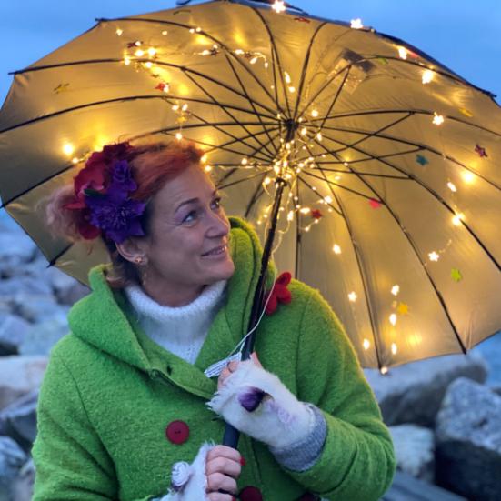 Sangpædagog Maria på en strand under en lysende paraply