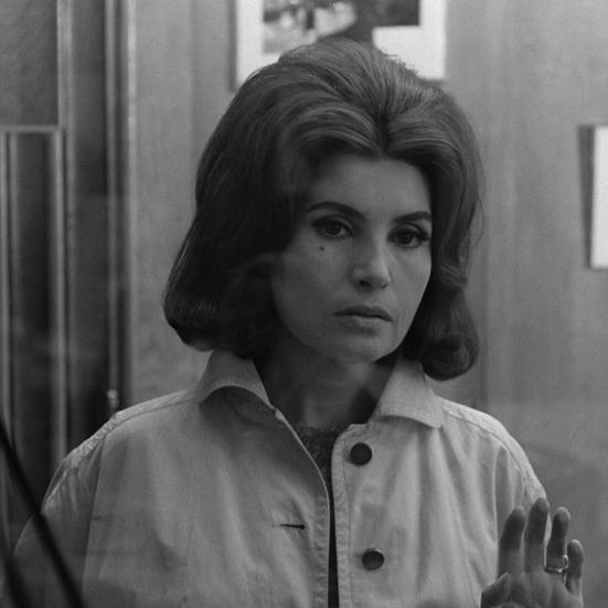 En kvinde der står og ser ind i kammeret, med jakke på