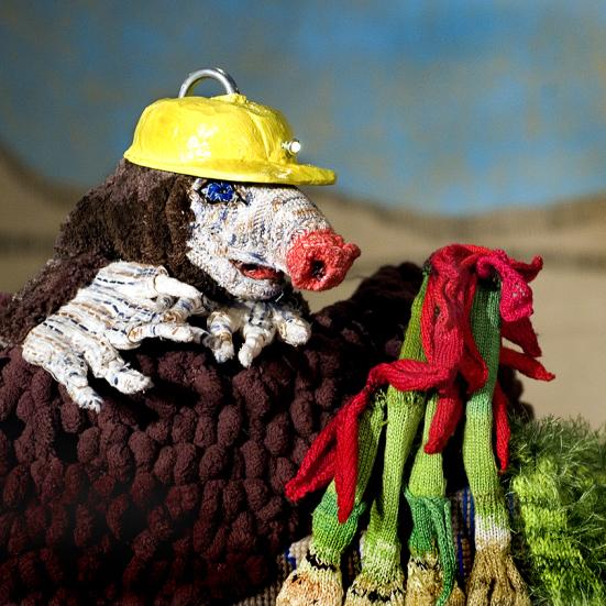 foto af en muldvarp hånddukke med en gul hjelm og en håndfuld af strikkede porrer