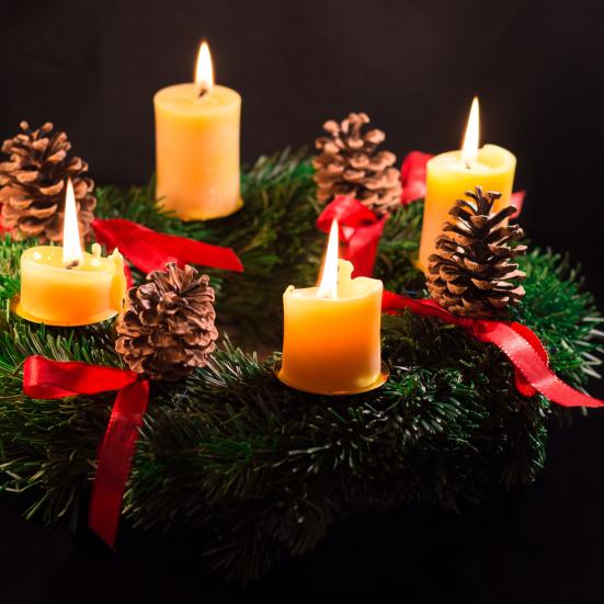 Adventskrans med 4 tændte lys i med sort baggrund