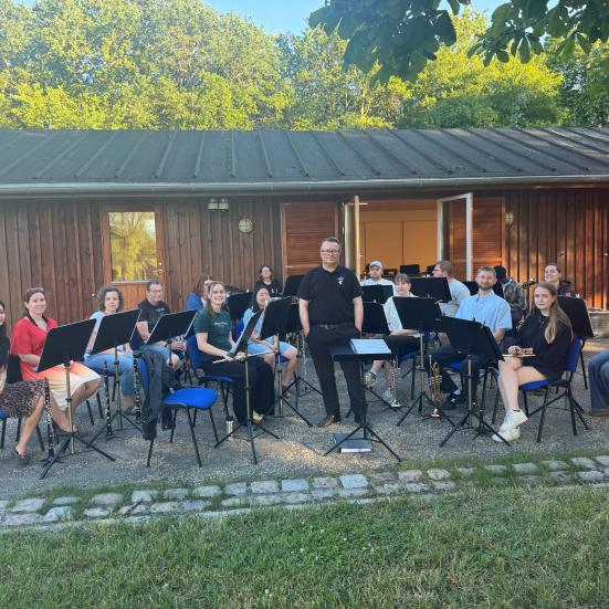 Orkester med musikere med instrumenter og dirigent stående i midten