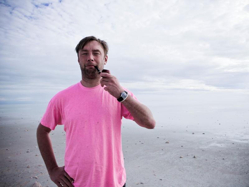 Nikolaj Kirk på en strand, der ryger en pibe. 