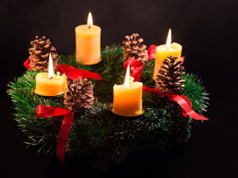 Adventskrans med 4 tændte lys i med sort baggrund