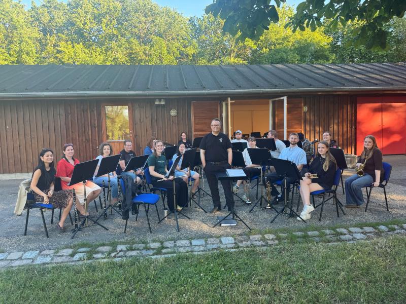 Orkester med musikere med instrumenter og dirigent stående i midten