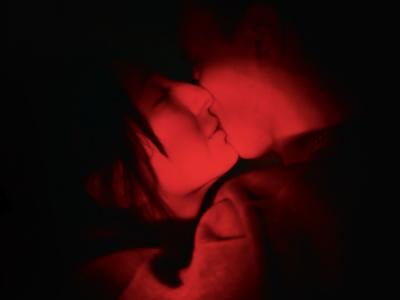 Et rødligt billede af to skikkelser der kysser