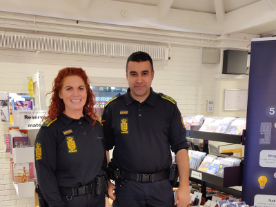 to betjente står og smiler venligt foran et bord med brochurer 