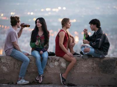 Fire unge mennesker drikker en øl og nyder udsigten