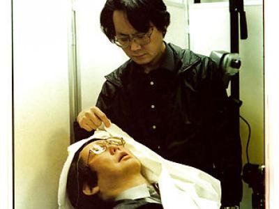 Mand i sort tøj der ser ned på en robot kopi af ham selv der ligger i en stol