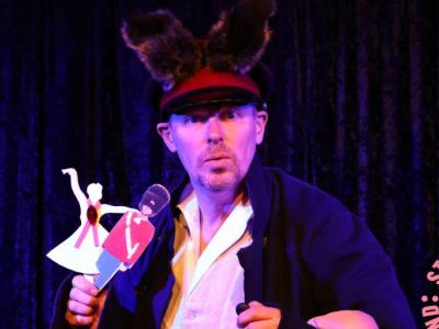 Mand med en stor hat og to dukker i hånden der ser ind i kammerat 