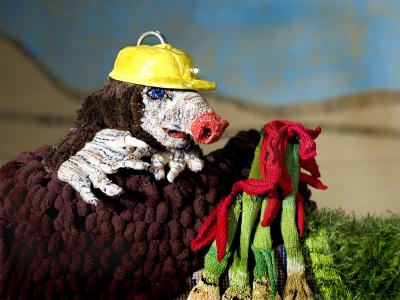 foto af en muldvarp hånddukke med en gul hjelm og en håndfuld af strikkede porrer