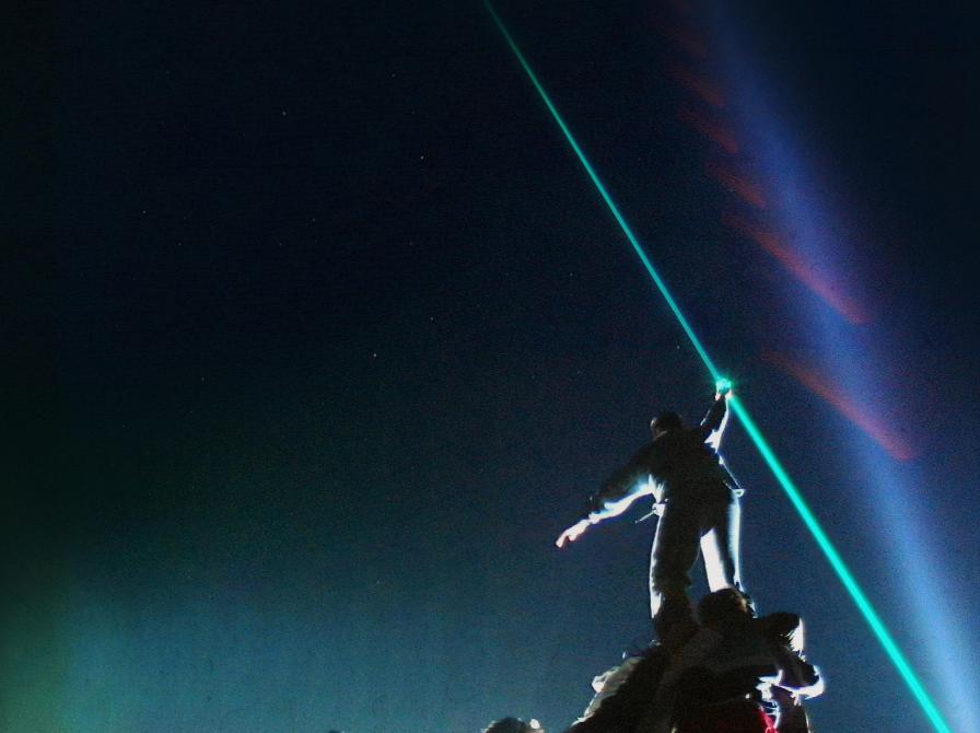 En person i silhuet mod himlen og en lysstråle der peger op i himlen