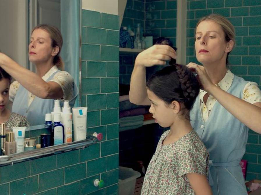 Kvinde på et badeværelse der sætter en mørkhåret piges hår.