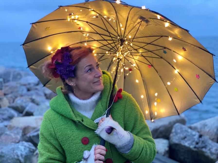 Sangpædagog Maria på en strand under en lysende paraply