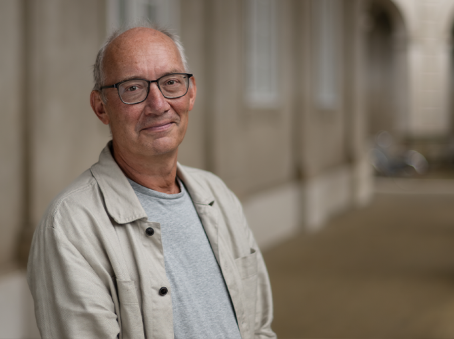 Mand der står med briller og ser ind i kameraet