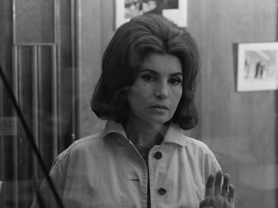 En kvinde der står og ser ind i kammeret, med jakke på